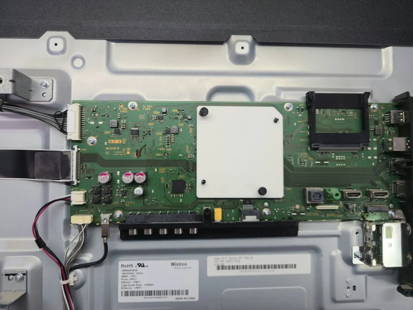Placa de bază a televizorului Sony KD-55XE8096 în timpul reparației, cu procesorul sub radiatorul alb și porturile HDMI și USB